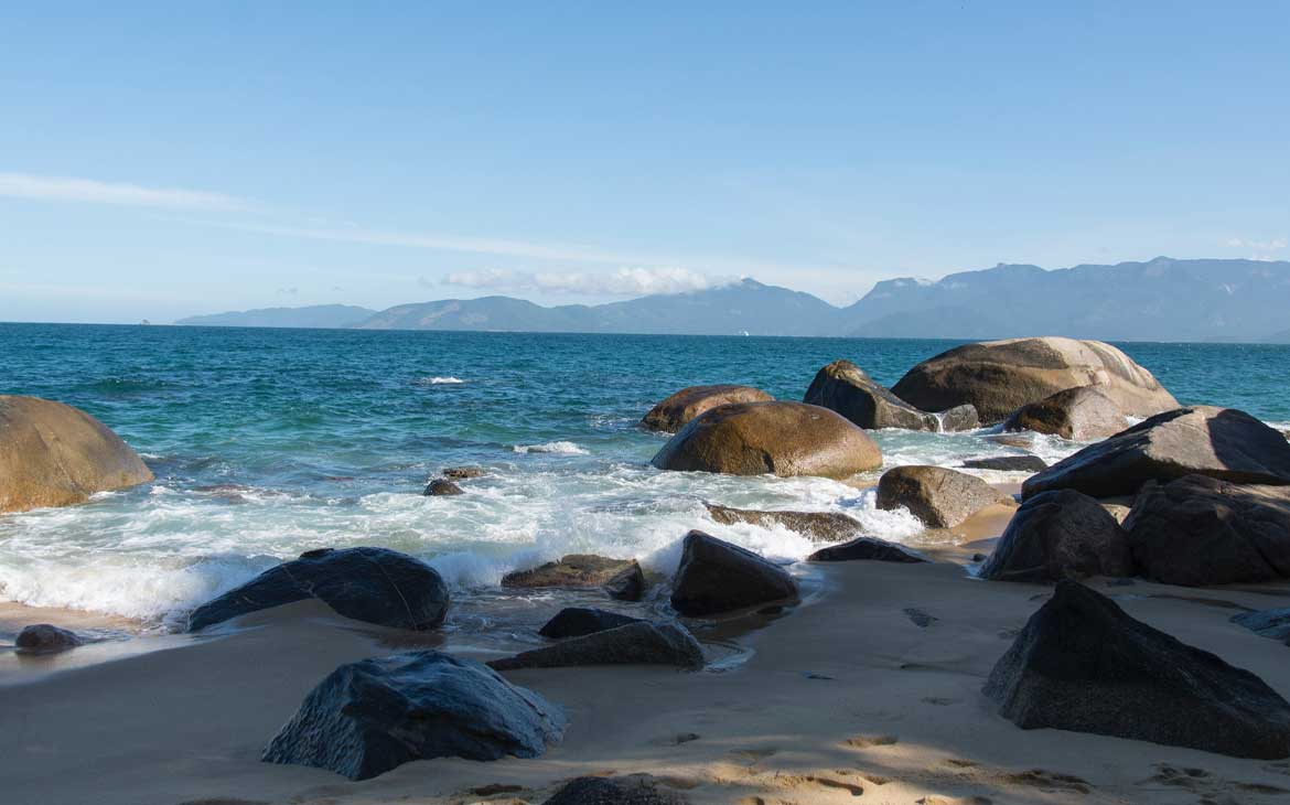 Foto, durante o dia, de rochas no mar de praia de Mangaratiba.